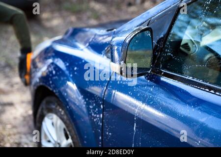 Person wäscht sein Auto selbst mit Mikrofaser Fäustlinge, warmes Wasser und Flüssigseife, Nahaufnahme Stockfoto