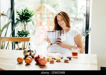 Schwangere Sommersprossen Rotschopf Frau Surfen Computer Gadget Tablet in sozialen Medien. Stockfoto