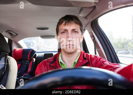 Vorderansicht des männlichen Fahrers, der in der Nähe des Lenkrads im Auto sitzt, kaukasischer Mann, der ein Fahrzeug fährt Stockfoto