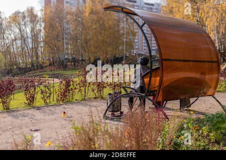 Die Urne im Park, ein Metallbehälter auf dem Rasen in der offenen Natur in der Nähe der Straße aus Steinen, Nachmittag bei sonnigem Wetter genießen Sie das Konzept. Gartenschaukeln. Stockfoto