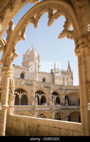 Kunstvolle manuelinische Architektur und Bögen mit Blick auf den gewölbten Glockenturm im Kreuzgang des Klosters Jerónimos in Lissabon, Portugal, Europa.
