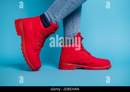 Cropped Profil Foto von fit Dame Beine Sneaker tiptoe tragen Stilvolle rote Gummischuhe Stiefel Denim Jeans isoliert teal Farbe Hintergrund Stockfoto