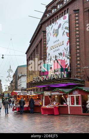 HELSINKI, FINNLAND-CIRCA DEZ, 2018: Neben dem Gebäude des Stockmann-Einkaufszentrums befinden sich Weihnachtsstände. Feiertagsbeleuchtung. Der Stockmann ist Stockfoto