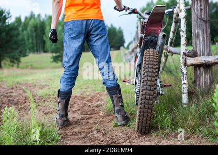 Männlicher Motorradfahrer ist bereit für Offroad-Fahren auf Off-Road-Motorrad mit Cross-Country-Reifen, Rückansicht Stockfoto