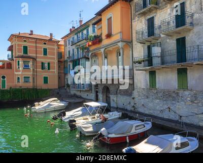 Motorboote in der Marina vor den schönen Häusern mit Blick auf den Comer See festgemacht.Lombardei, Italien Stockfoto