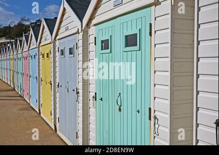 Lyme Regis, Dorset und weiche, pastellfarbene Holztüren zieren Strandhütten an der Strandpromenade. Stockfoto