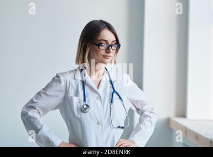 Professionelle Ärztin steht neben dem Fenster und einem Stethoskop Um ihren Hals Stockfoto