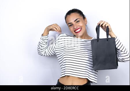Junge schöne Frau mit einer schwarzen Einkaufstasche mit einem erfolgreichen Ausdruck. Schwarzer Freitag Stockfoto