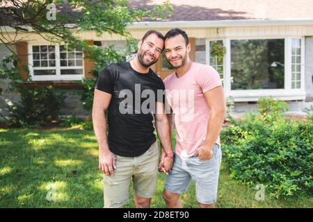 Ein Porträt von einem glücklichen schwulen Paar draußen vor Eines neuen Kaufs Stockfoto