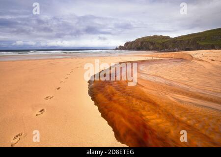 Der rote Fluss fließt hinunter zum Dalmore Strand am Isle of Lewis Stockfoto