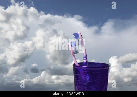 Ein Paar Zahnbürsten im Glas vor Ein Himmel mit Wolken Stockfoto