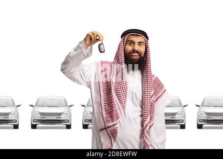 Arabischer Mann in einem Thobe hält Autoschlüssel in einem Ausstellungsraum isoliert auf weißem Hintergrund Stockfoto