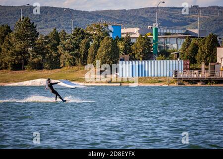 Mann wird auf einem Wakeboard auf einem See gezogen Stockfoto