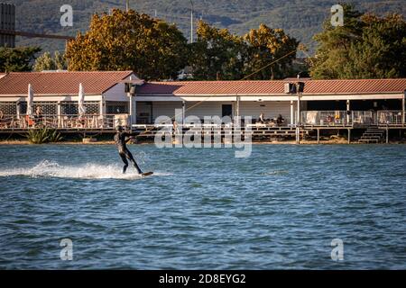 Mann wird auf einem Wakeboard auf einem See gezogen Stockfoto