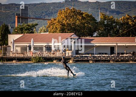 Mann wird auf einem Wakeboard auf einem See gezogen Stockfoto