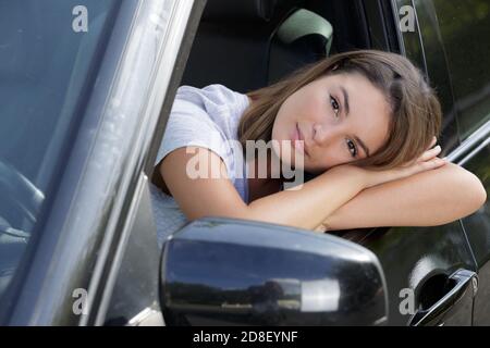 dame, die sich durch das offene Fenster an die Autotür lehnte Stockfoto
