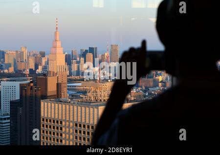 Die Silhouette eines Besuchers, der Fotos von Tokio gemacht hat Stadtbild von der Aussichtsplattform der Tokyo Metropolitan Government aus gesehen Gebäude mit NTT Docomo Yoyogi Gebäude im Vordergrund.Shinjuku.Tokyo.Japan Stockfoto