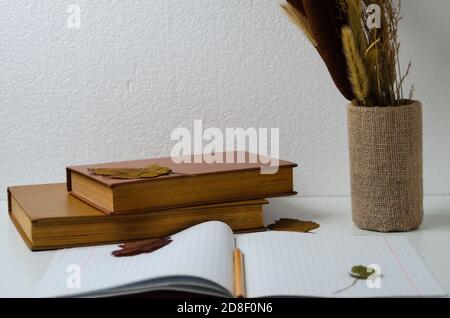 Notizbuch mit einem Lesezeichen aus vierblättrigen Kleeblatt auf dem Hintergrund eines alten Buches, Herbststrauß und Blätter Selektiver Fokus. Stockfoto