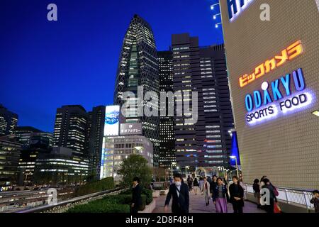 Nachtansicht der Shinjuku Station mit Mode Gakuen Cocoon Tower Im Hintergrund und Odakyu Kaufhaus im Vordergrund.Shinjuku.Tokyo.Japan Stockfoto