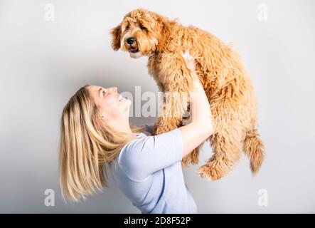 Frau mit seinem Golden Labradoodle Hund isoliert auf weißem Hintergrund Stockfoto