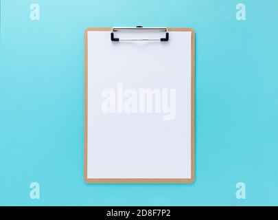 Eine hölzerne Zwischenablage mit weißem Papier auf blauem Hintergrund Stockfoto