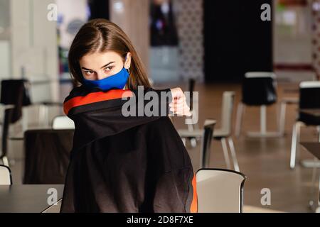 Porträt einer jungen Frau in blauer Schutzmaske, Niesen und deckt mit ihrem Ellbogen. Coronavirus Schutz und Prävention. Stockfoto