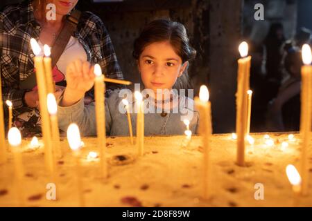 Ein Mädchen zündet eine Kerze im Gebet an der Jvari Kirche an, einer der heiligsten Stätten Georgiens in Mzcheta, Georgien, Kaukasus, Europa. Stockfoto