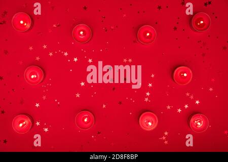 Weihnachtsabend oder Valentinstag Komposition aus brennenden Kerzen, Glitzer auf roter Oberfläche. Frohe weihnachten und glückliches Neues Jahr 2021, glücklich Stockfoto