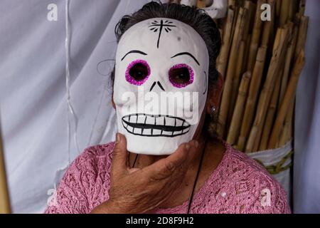 Mexiko-Stadt, Mexiko. Okt. 2020. MEXIKO-STADT, MEXIKO - OKTOBER 29: Eine Frau posiert mit einer Maske aus Karton-Schädeln im Outdoor-Markt werden Karton-Schädel als Ornamente in Opfergaben während der mexikanischen Tag der Toten ( Dia de Muertos) Traditionen verwendet. Aus diesem Anlass werden die Feierlichkeiten zum Tag der Toten, wie Paraden, und der Besuch der Friedhöfe aufgrund der neuen Coronavirus-Pandemie unterbrochen. Am 29. Oktober 2020 in Mexiko-Stadt, Mexiko. Kredit: Fernando Camacho/Eyepix Gruppe/Der Fotozugang Gutschrift: Der Fotozugang/Alamy Live Nachrichten Stockfoto