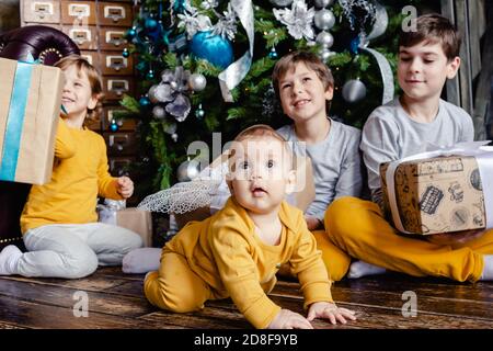 Glückliche Kinder Brüder Eröffnung Geschenke vor Weihnachtsbaum. Weihnachtszeit. Konzentrieren Sie sich auf das Baby. Stockfoto