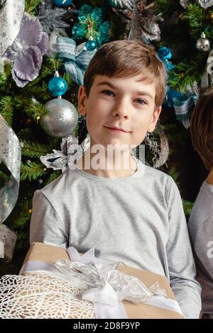 Lächelndes, lustiges Kind, das Weihnachtsgeschenk in der Hand hält. Weihnachtskonzept. Weihnachtszeit. Stockfoto