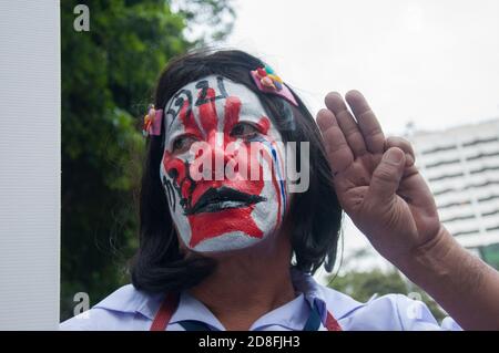 Bangkok, Thailand. Okt. 2020. Ein Protestler mit einem Gesichtsbemalung lässt den dreifingerigen Gruß während der Demonstration zu. Tausende von prodemokratischen Demonstranten gingen in Silom auf die Straße und forderten den Rücktritt des thailändischen Premierministers und die Reform der Monarchie. Der Protest wurde von der Free Youth Group unter dem Motto „People's Runway“ organisiert, mit einem modischen 'roten Teppich', Tanz, Performance, Show und Musik. Kredit: SOPA Images Limited/Alamy Live Nachrichten Stockfoto