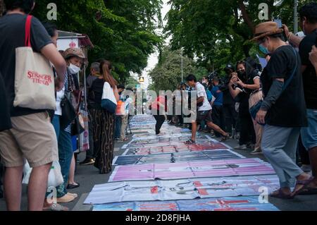 Bangkok, Thailand. Okt. 2020. Während der Demonstration treten Demonstranten auf die Plakate, die auf dem Boden liegen.Tausende von prodemokratischen Demonstranten gingen in Silom auf die Straße und forderten den Rücktritt des thailändischen Premierministers und die Reform der Monarchie. Der Protest wurde von der Free Youth Group unter dem Motto „People's Runway“ organisiert, mit einem modischen 'roten Teppich', Tanz, Performance, Show und Musik. Kredit: SOPA Images Limited/Alamy Live Nachrichten Stockfoto