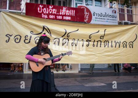 Bangkok, Thailand. Okt. 2020. Ein Protestler, der während der Demonstration eine Gitarre vor einem Banner spielt, auf dem der Royalist Marketplace steht.Tausende von prodemokratischen Demonstranten gingen in Silom auf die Straße und forderten den Rücktritt des thailändischen Premierministers und die Reform der Monarchie. Der Protest wurde von der Free Youth Group unter dem Motto „People's Runway“ organisiert, mit einem modischen 'roten Teppich', Tanz, Performance, Show und Musik. Kredit: SOPA Images Limited/Alamy Live Nachrichten Stockfoto