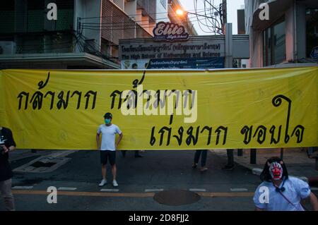 Bangkok, Thailand. Okt. 2020. Ein Protestler mit Gesichtsmaske steht vor einem Transparent, auf dem er sehr mutig, sehr gut, Danke während der Demonstration sagt.Tausende von pro-demokratischen Demonstranten gingen in Silom auf die Straße und forderten den Rücktritt des thailändischen Premierministers und die Reform der Monarchie. Der Protest wurde von der Free Youth Group unter dem Motto „People's Runway“ organisiert, mit einem modischen 'roten Teppich', Tanz, Performance, Show und Musik. Kredit: SOPA Images Limited/Alamy Live Nachrichten Stockfoto