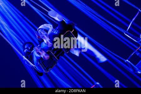 Hannover, Deutschland. Oktober 2020. Passagiere sitzen auf der Herbstmesse in Hannover in einem Kettenkarussell. Quelle: Peter Steffen/dpa/Alamy Live News Stockfoto