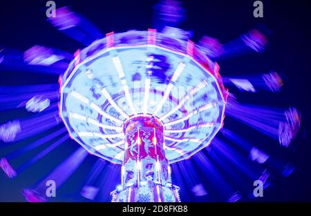 Hannover, Deutschland. Oktober 2020. Ein Kettenkarussell leuchtet vor dem Abendhimmel auf der Herbstmesse in Hannover. Quelle: Peter Steffen/dpa/Alamy Live News Stockfoto