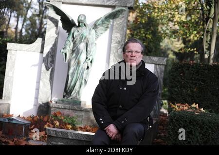 Köln, Deutschland. Oktober 2020. Christoph Kuckelkorn, Bestattungsdirektor und Karnevalspräsident, sitzt an einem Grab im Melatenfriedhof. (An dpa 'mit Faschingspräsident Christoph Kuckelkorn im Melatenfriedhof') Quelle: Oliver Berg/dpa/Alamy Live News Stockfoto