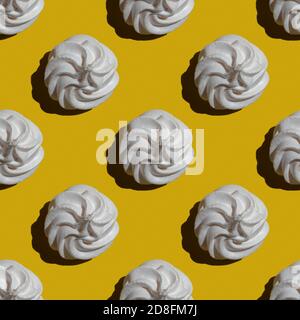 Nahtloses Marshmallow- oder Meringue-Muster auf gelbem Hintergrund isoliert. Süßigkeiten und Essen Themen. Geeignet für Tapete, Textil, Hintergrund, Poster, b Stockfoto