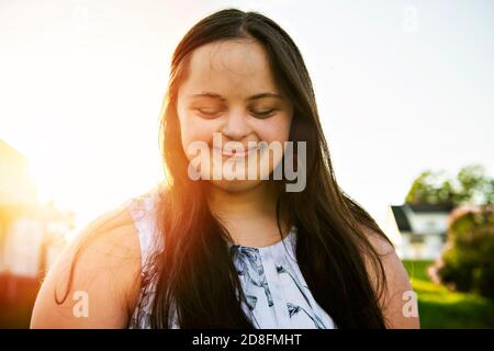 Ein Porträt von trisomie 21 Erwachsene Mädchen draußen bei Sonnenuntergang Stockfoto