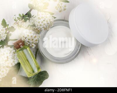 Nahaufnahme von Bio-Öl und Creme. Grüne kosmetische Anordnung, frische Kräuter-Hautpflege Kosmetik. Ätherisches Öl, Handwerk Flasche, Blumen, Glas Gesichts c Stockfoto