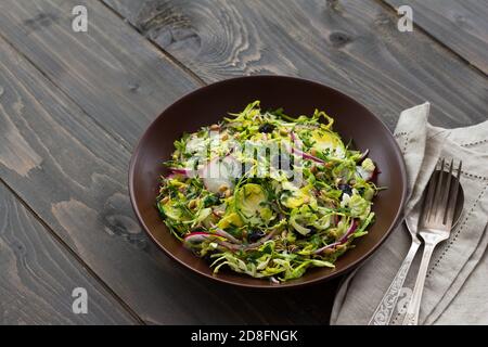 Salat aus rosenkohl mit Rettich, Rosinen und Weizensprossen. Gesunde Ernährung Detox Lebensmittel. Auf einem hölzernen Hintergrund in einem rustikalen Stil Stockfoto