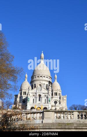 Basilika des Heiligen Herzens von Paris. Berühmte Basilika Sacr-Cur, Paris, Frankreich. Blauer Hintergrund und im Herbst mit Baumfront. Stockfoto