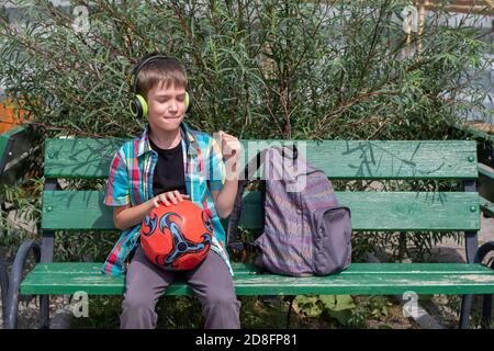 Ein süßer Junge Schuljunge in lässiger Kleidung trägt Musik mit Kopfhörern. Zurück zur Schule Konzept Stockfoto