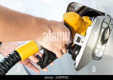 Gelbe Düse mit Handhaltung zum Tanken des Fahrzeugs bei Gas Station Stockfoto