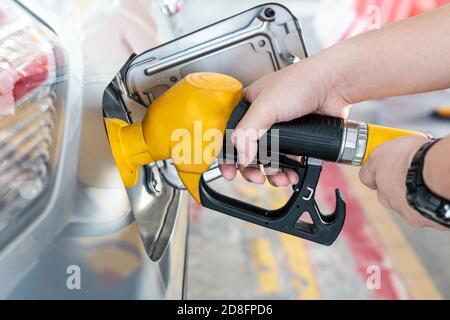 Gelbe Düse mit Handhaltung zum Tanken des Fahrzeugs bei Gas Station Stockfoto