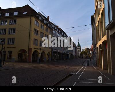 Freiburg, Baden-Württemberg, Deutschland - 10/25/2020: Leere Einkaufsstraße Kaiser-Joseph-Straße mit geschlossenen Geschäften und historischem Tor Martinstor. Stockfoto