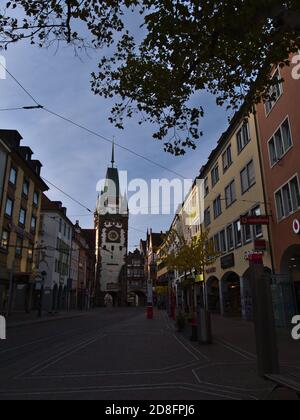 Freiburg, Baden-Württemberg, Deutschland - 10/25/2020: Verlassene Einkaufsstraße Kaiser-Joseph-Straße mit geschlossenen Geschäften und historischem Tor Martinstor. Stockfoto