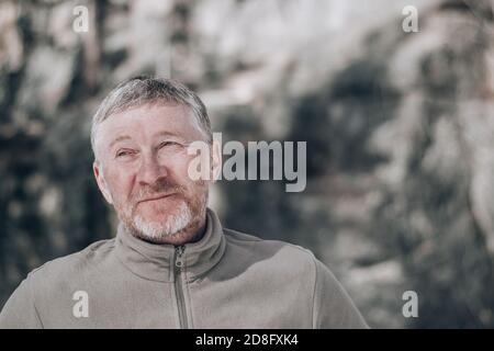 Porträt eines unrasierten attraktiven und glücklichen Mann mittleren Alters im Freien. Schaut mit einem Lächeln auf. Menschen und Lifestyle-Konzept. Leerzeichen für Text. Stockfoto