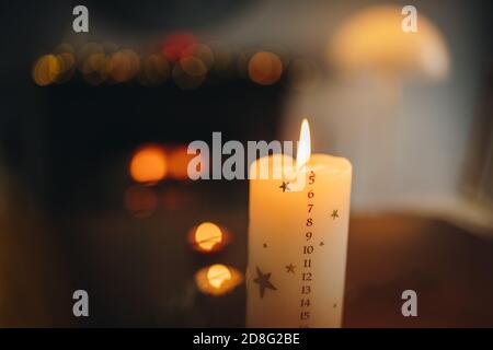 Nahaufnahme einer brennenden weihnachtskerze. Countdown zu Weihnachten auf brennende Kerze mit dezember Monat Datum Zahlen. Stockfoto